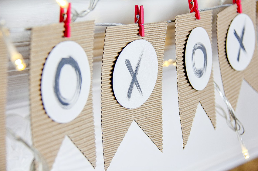 a pennant banner for Valentine's Day made out of corrugated cardboard and stamped with hugs and kisses