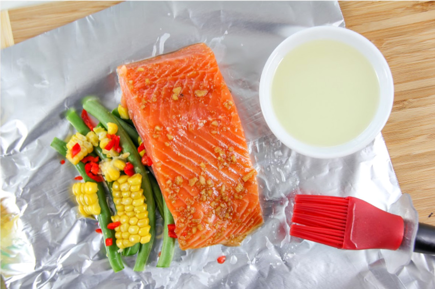 Salmon in a foil packet with green beans, corn, and peppers.