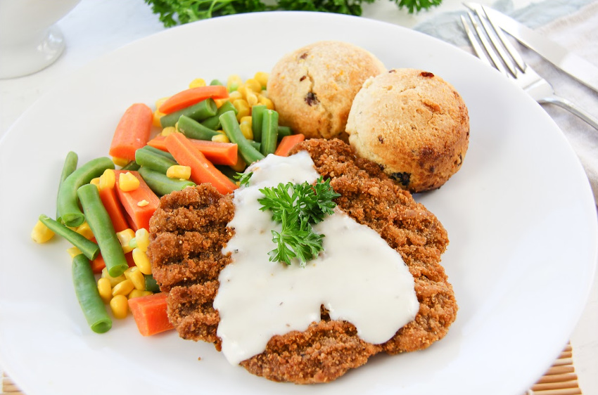 Country fried steak with mixed vegetables, biscuits, and gravy.