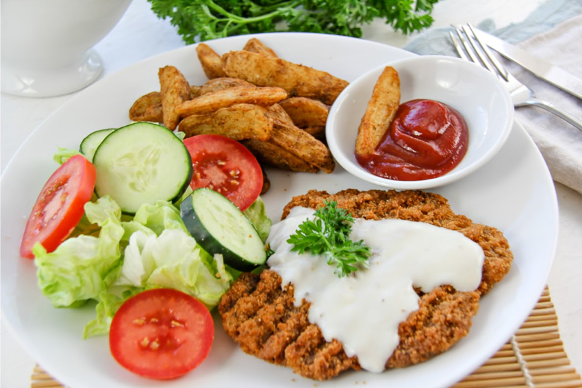 Country fried steak with wedges and salad.