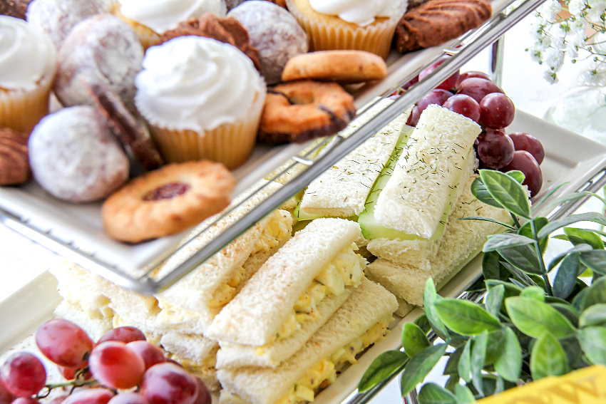 Trays of food for an afternoon tea party including finger sandwiches.