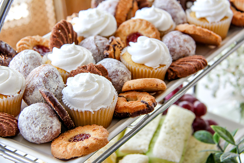 Assorted cookies, mini cupcakes, and donut holes on a tray for an afternoon tea party.