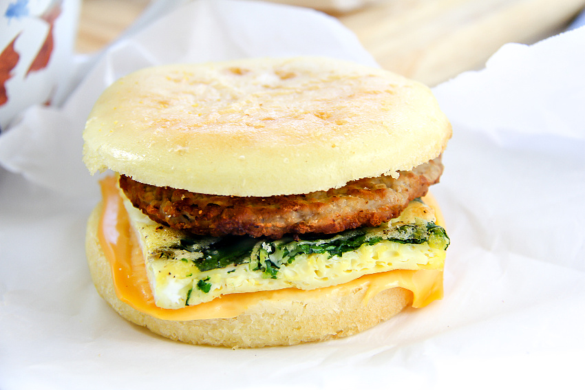 A gluten-free freezer breakfast sandwich with egg, cheese, spinach, and sausage.
