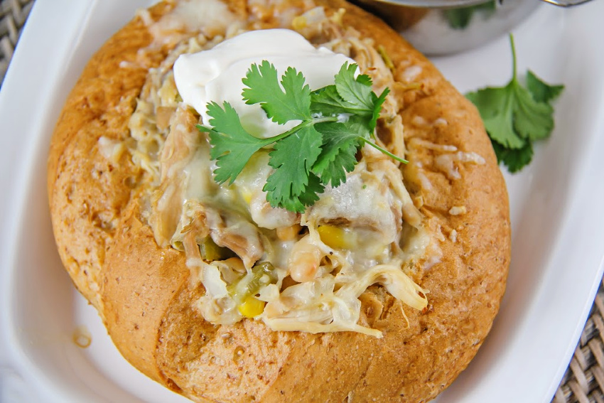 chicken chili in a bread bowl topped with cream and parsley