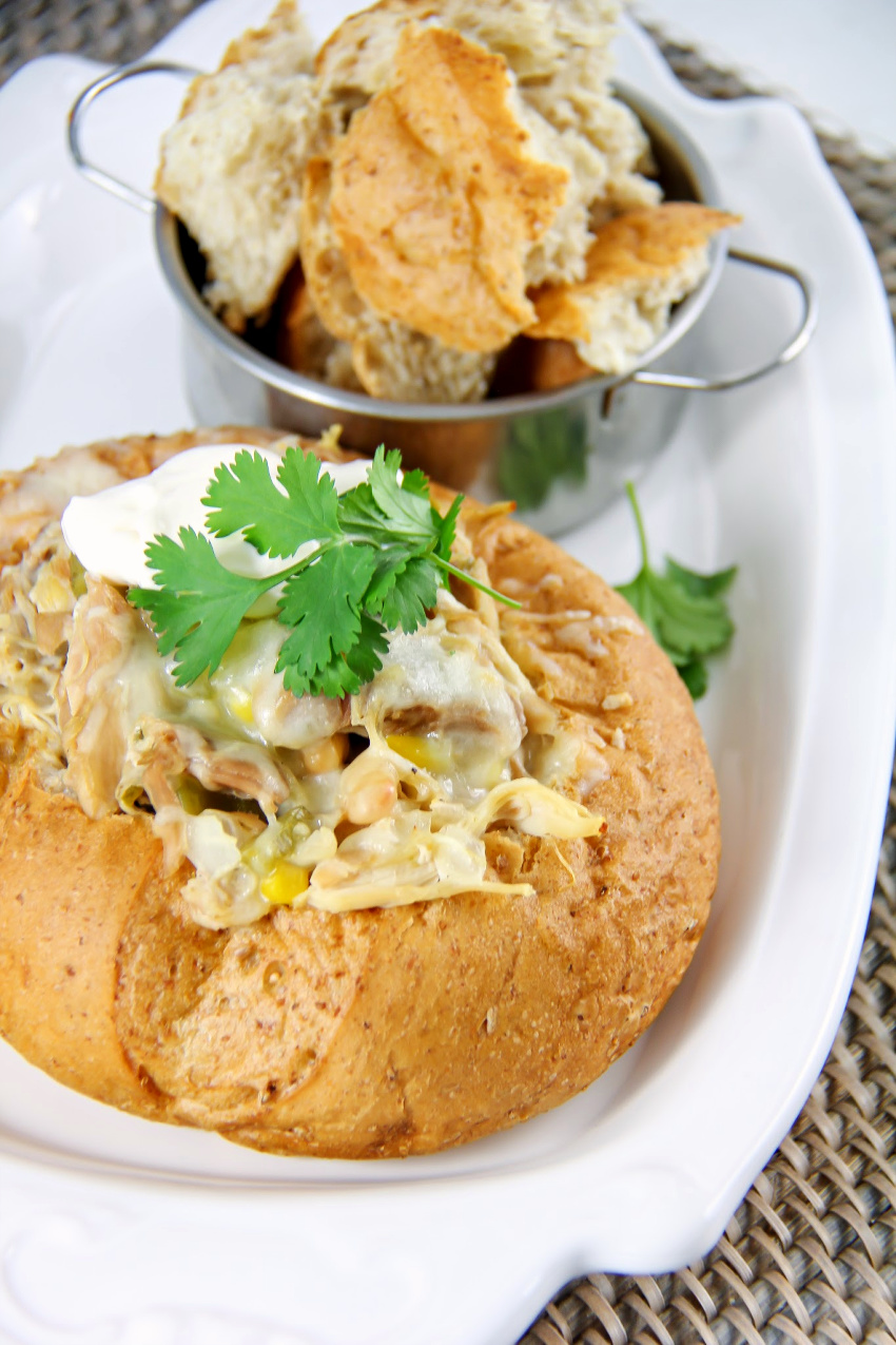 chicken chili topped with fresh parsley in bread bowls on a white plate