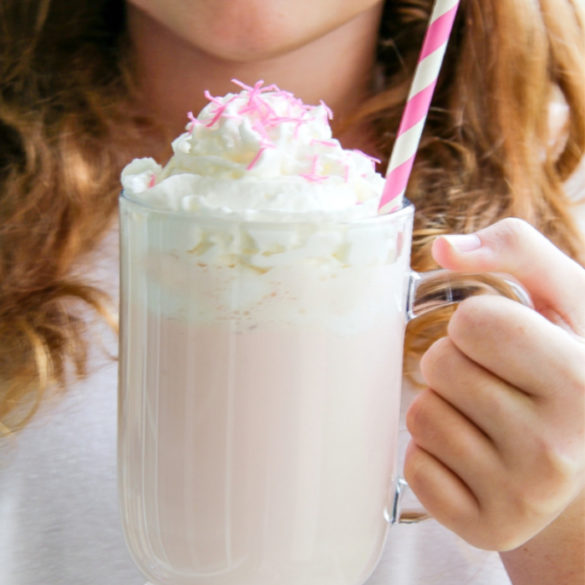 girl holding a pink hot chocolate in a clear mug