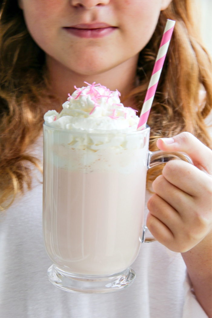 girl holding a pink hot chocolate in a clear mug