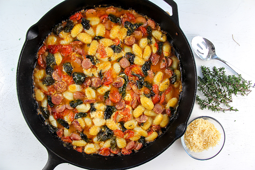 a cast-iron pan with gnocchi and kielbasa and cooked produce