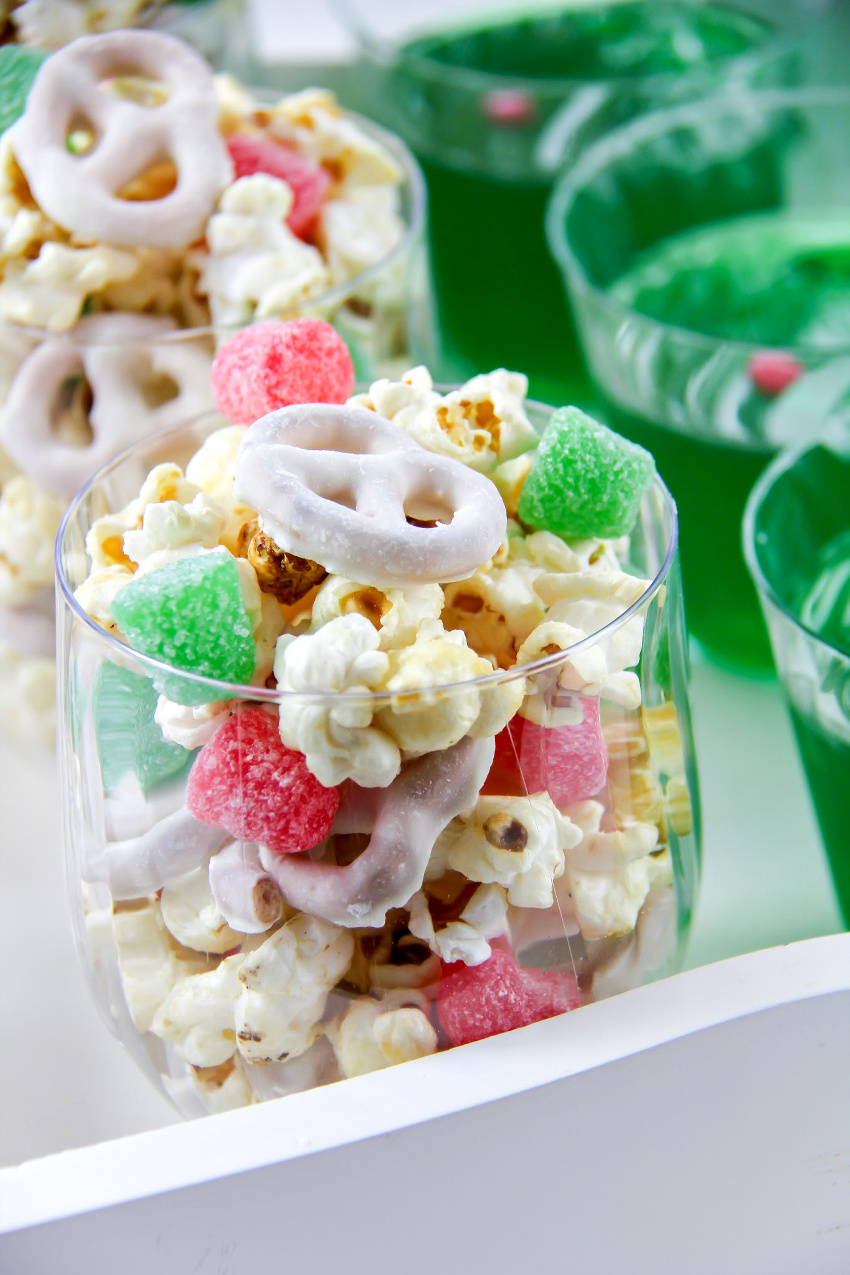 popcorn, yogurt covered pretzels, and red and green candy in a cup