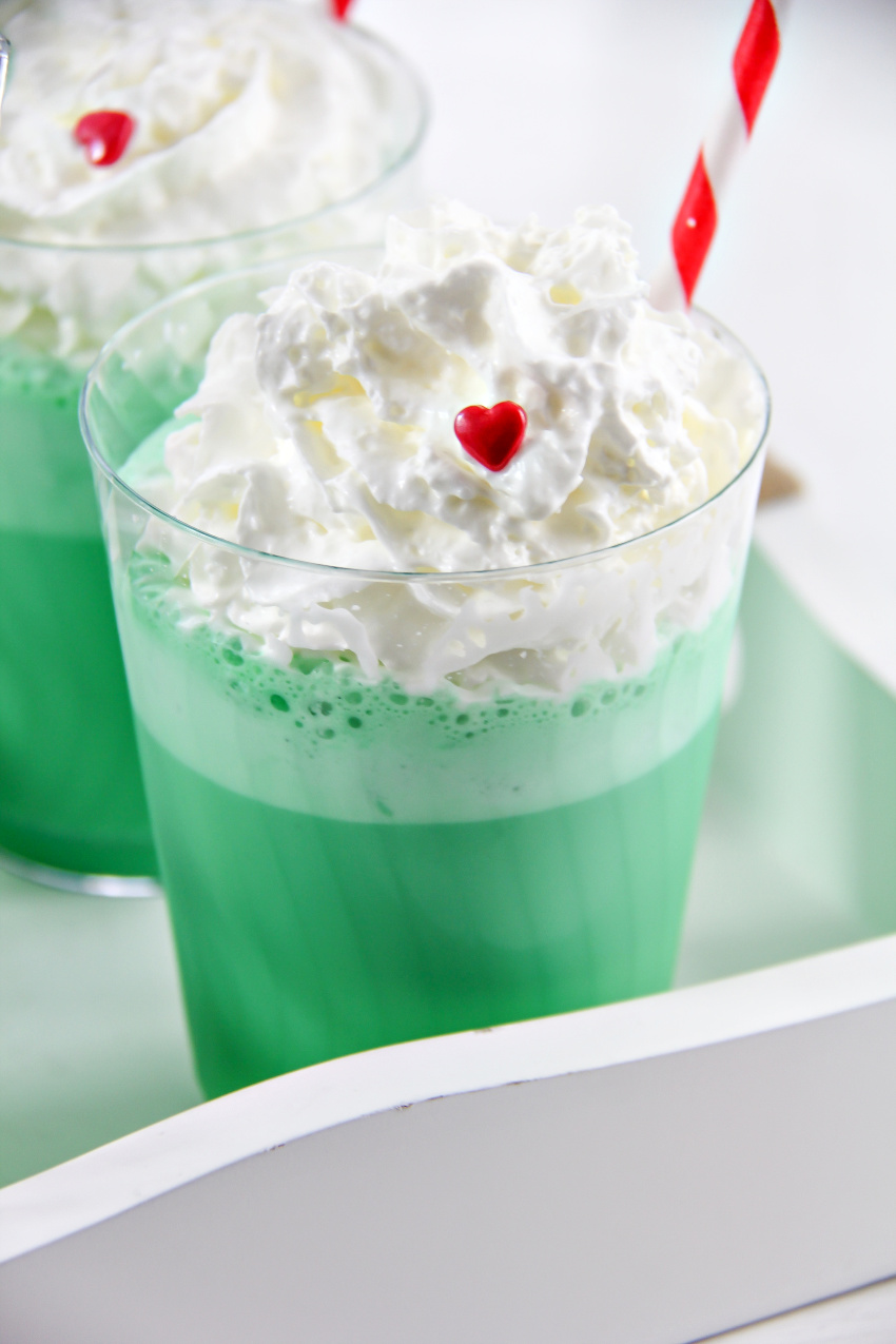 a green milkshake with whipped cream and a red candy heart