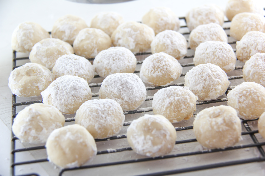 lemon snowball cookies on a wire rack dusted in confectioners sugar