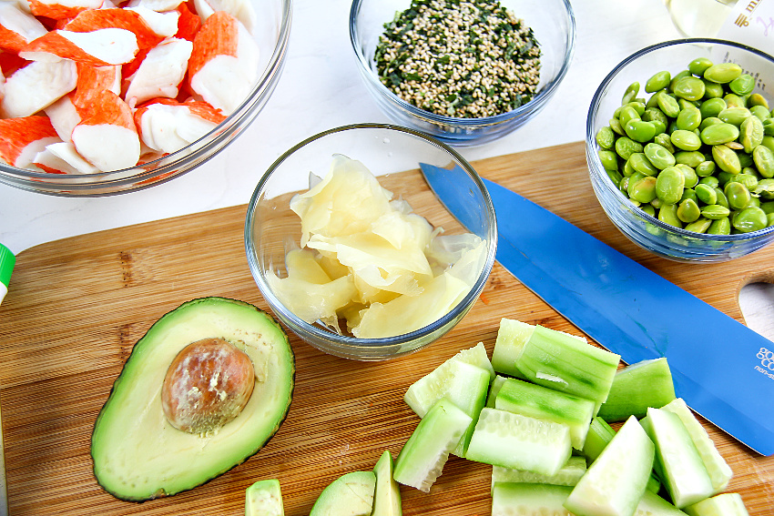 sushi ginger in a bowl surrounded by avocado, cucumber, edamame, and other sushi ingredients