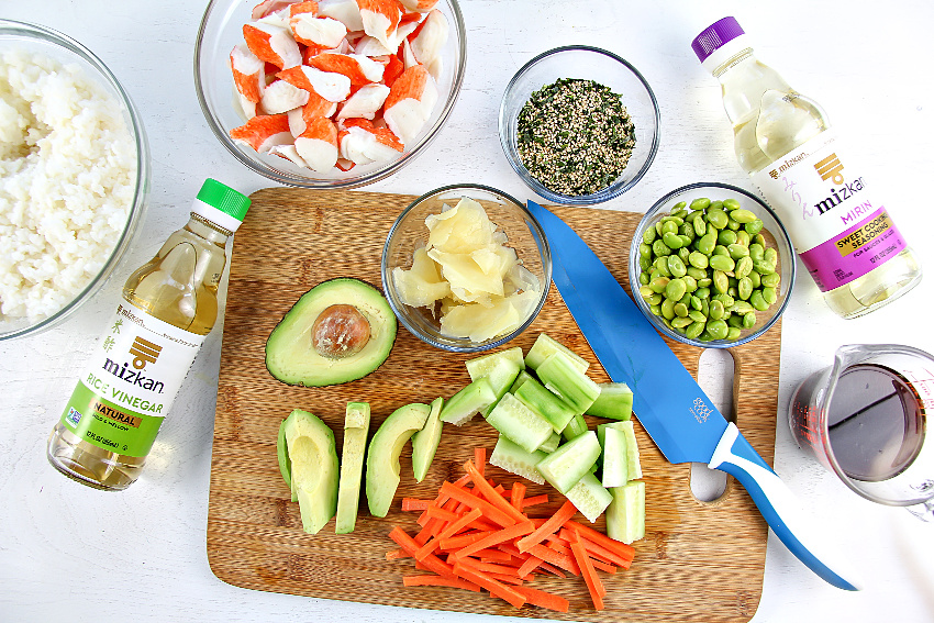Avocado slices, imitation crab meat, edamame, sushi rice, carrot, and other ingredients to make a sushi bowl