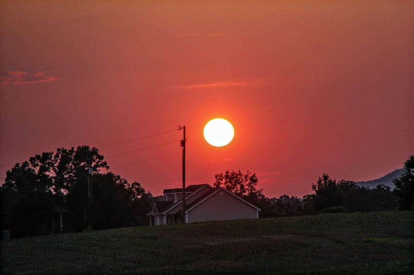 A red sky and sunset over a farmhouse in the country