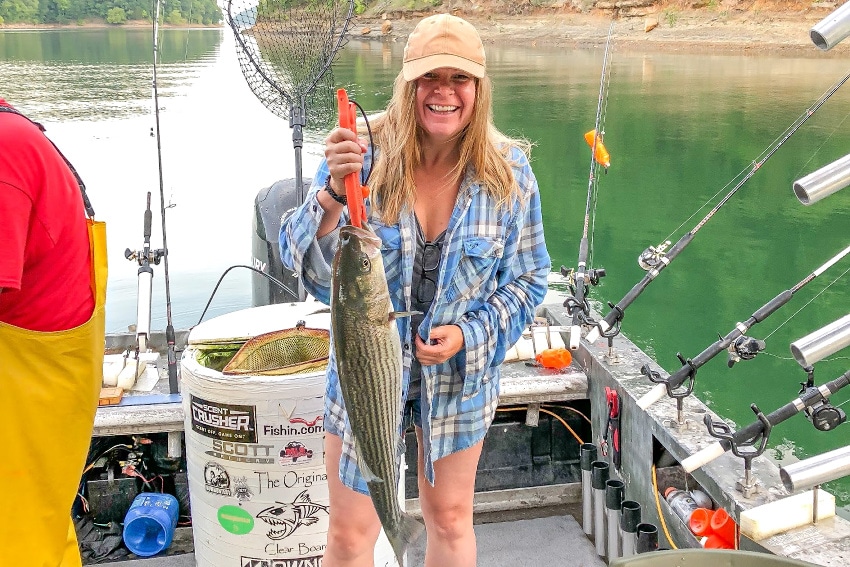 A lady holding a fish on a fishing boat