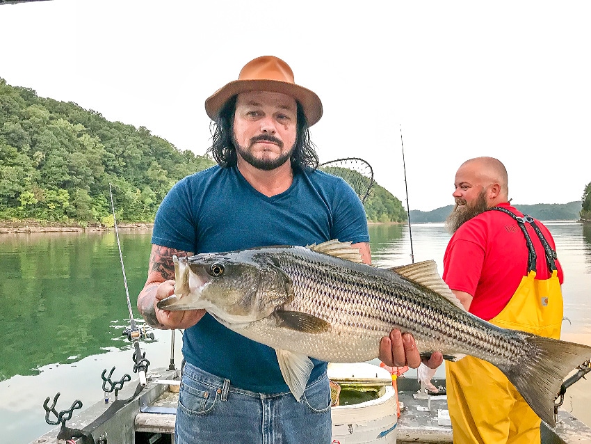 A man holding a fish on a fishing boat