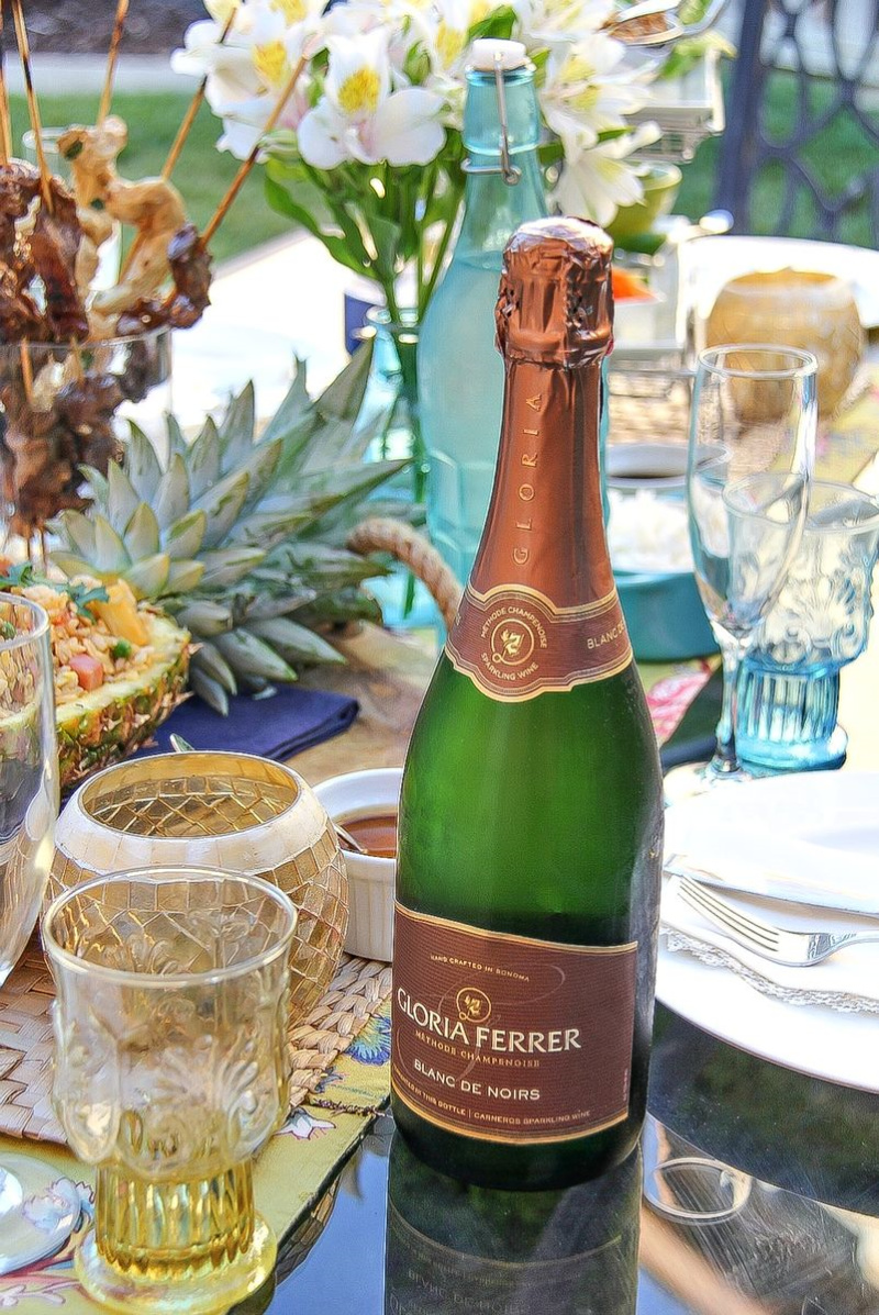 A bottle of Gloria Ferrer Sparkling on an outdoor table with Thai food.