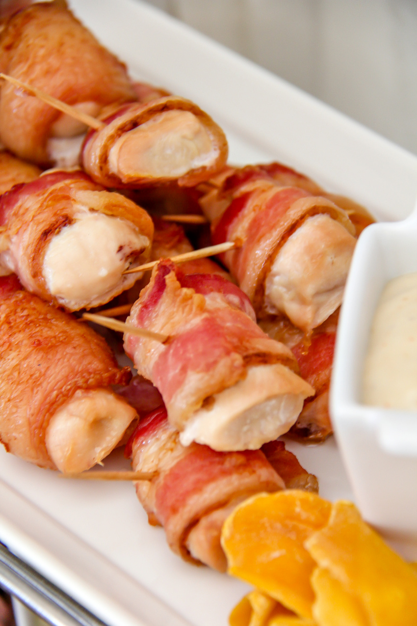 chicken pieces wrapped in bacon on a white tray