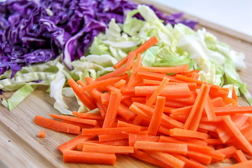 green and red cabbage with carrots on a cutting board