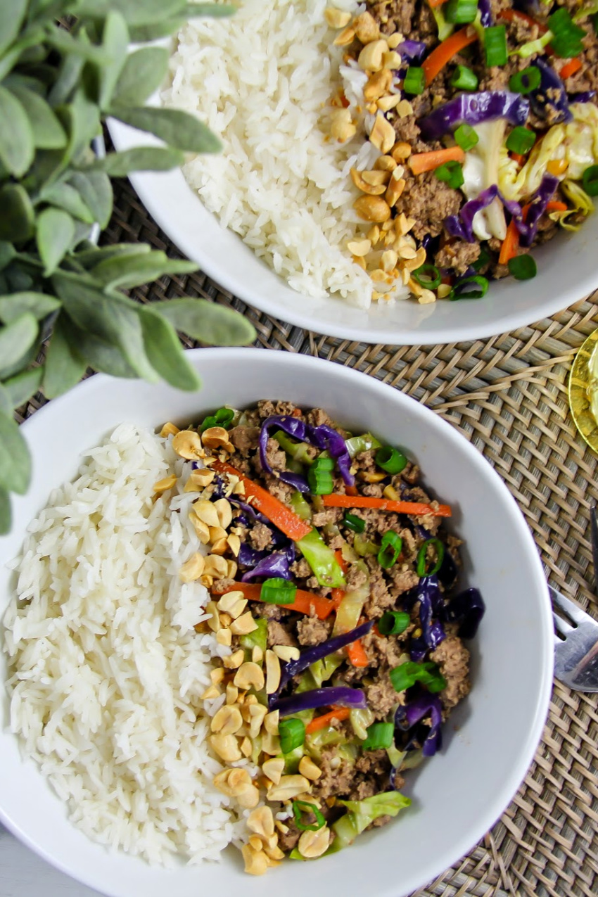 white bowls with rice on one side and ground turkey with cabbage, carrots, and green onions on the other and peanuts down the center