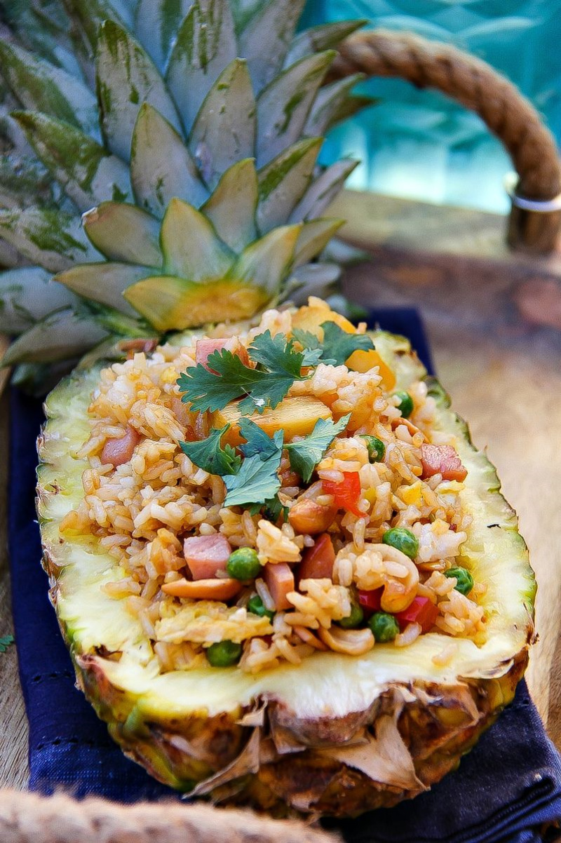 Fried rice in a half pineapple on a wood tray