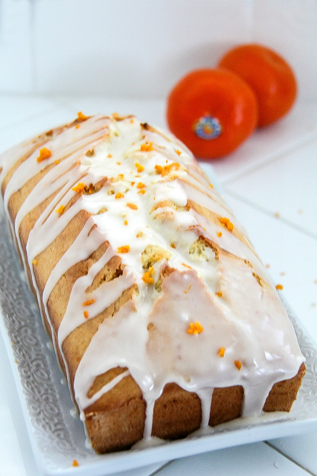 a mandarin loaf cake with a glaze and mandarin peel over it