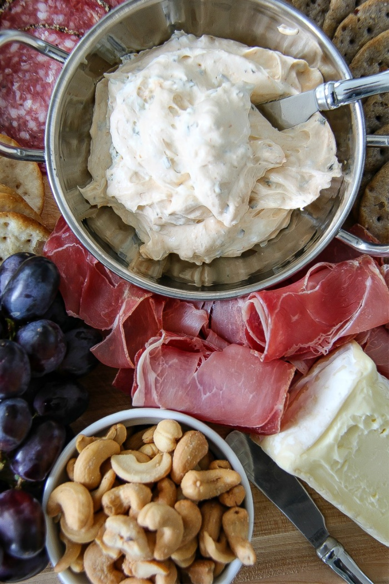 cream cheese spread in a silver bowl surrounded by meat and fruit