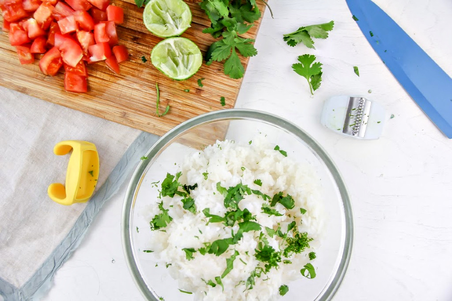 chopped tomato, lime, and cilantro on a cutting board and cilantro lime rice in a bowl