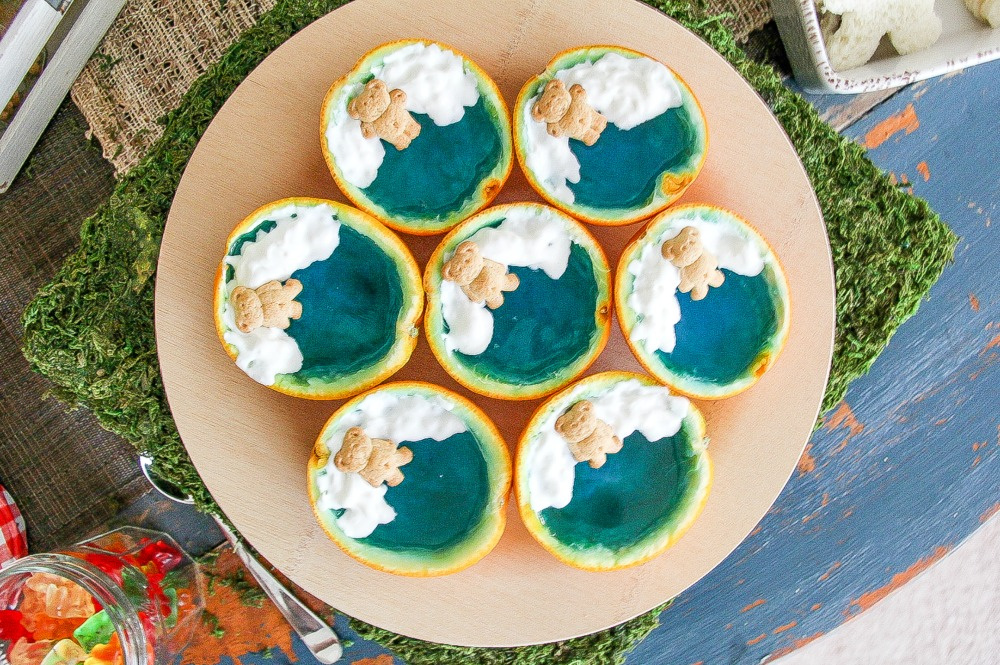 orange halves filled with blue jelly with whipped cream and a teddy bear cracker on top