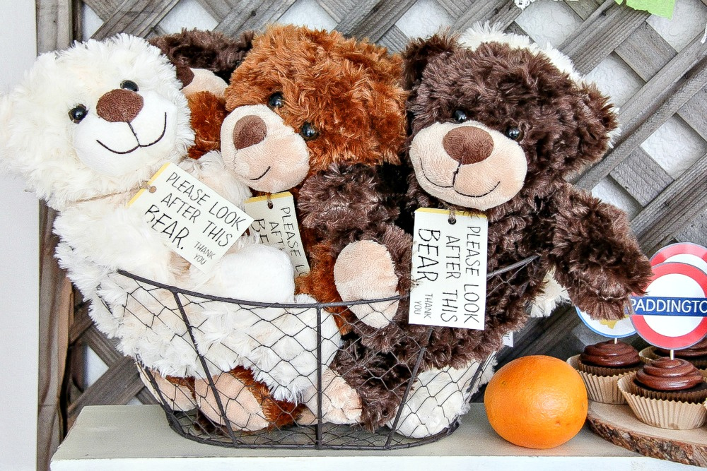 small teddy bears in a basket with a sign around their neck from paddington