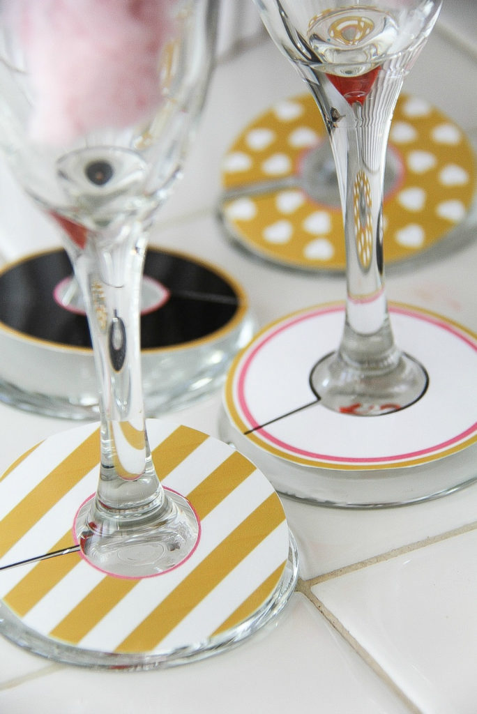 paper glass markers in black, gold, pink, and white wrapped around champagne glasses