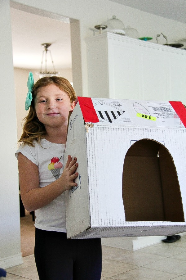 a girl making a cardboard box dog kennel