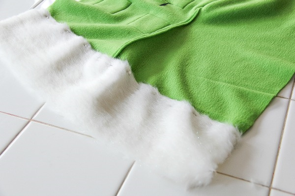 a piece of fur pinned to the top of a green fleece stocking