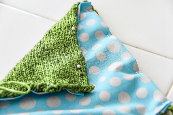 blue and white spotted fabric pinned to green knitting