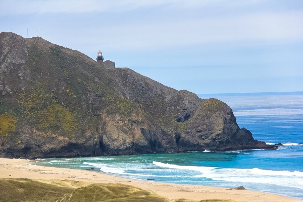 a lighthouse on a cliff by the ocean in big sur