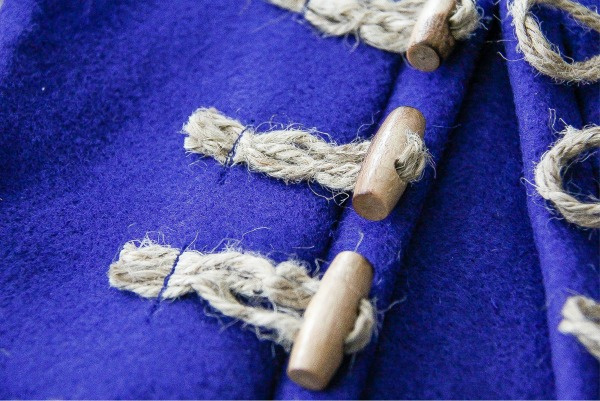 a wood toggle with rope through it sew onto blue felt to close a coat