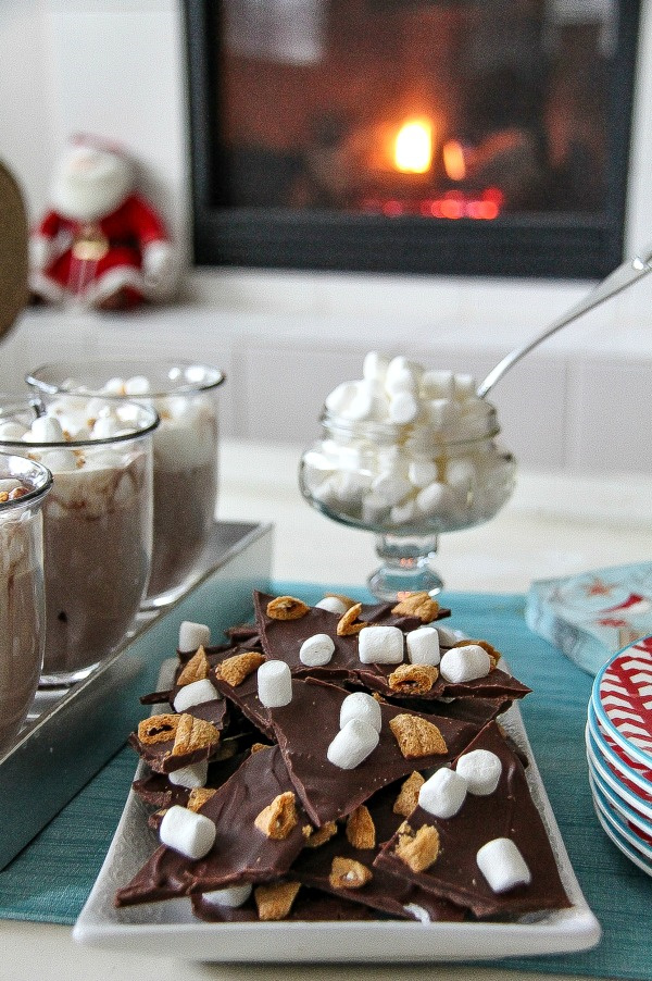 s'mores treats and hot chocolate on a table in front of a fire