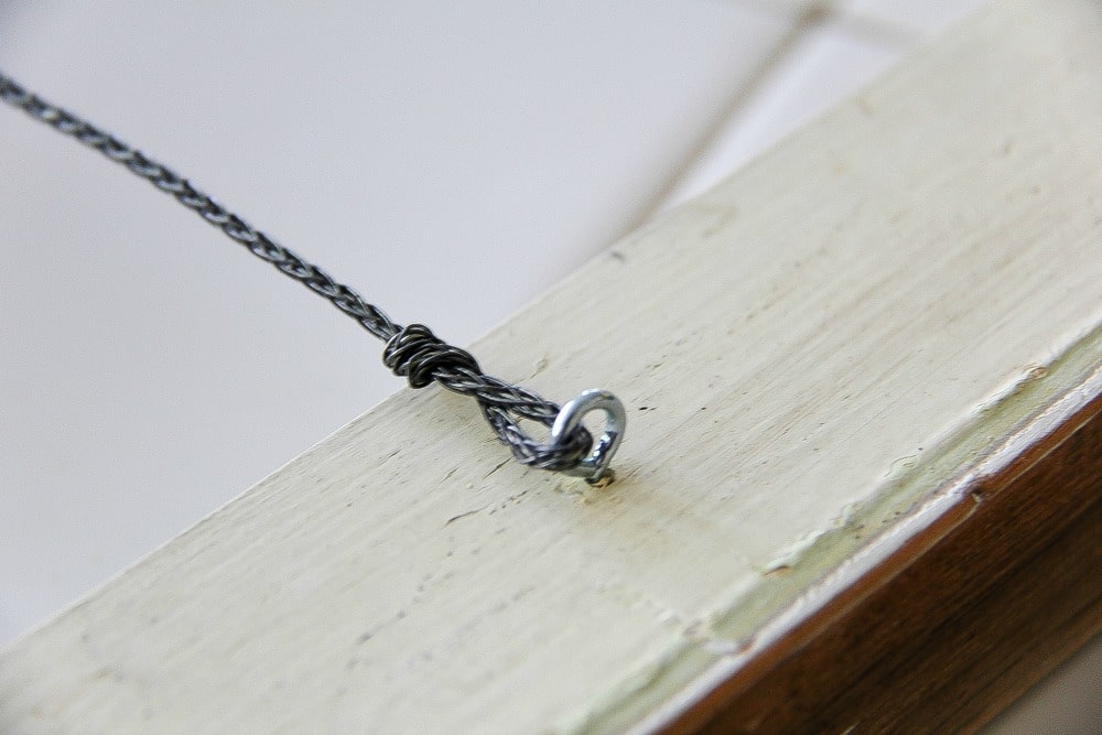 a hook and eye with wire attached to a wood frame
