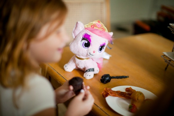 Aurora plush kitty sitting on a table while a girl eats breakfast