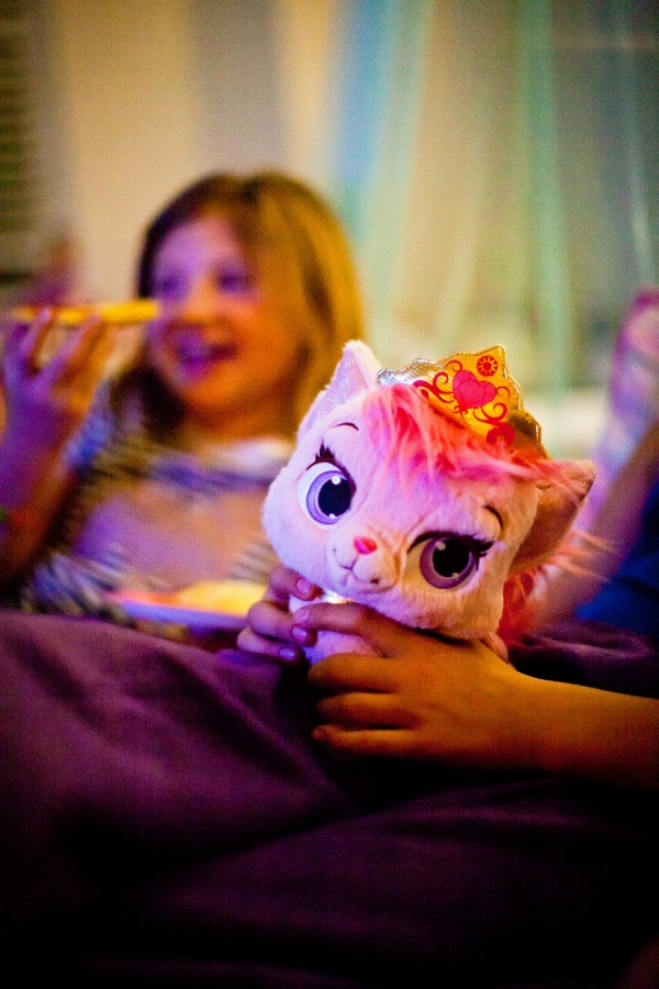 a girl smiling and a plush Disney kitty during a sleepover