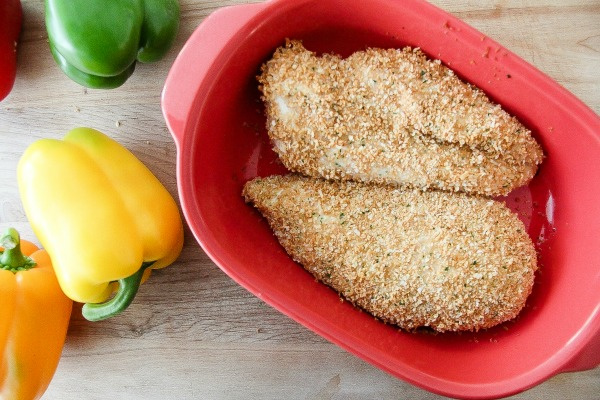 chicken breasts in a baking dish covered in breadcrumbs