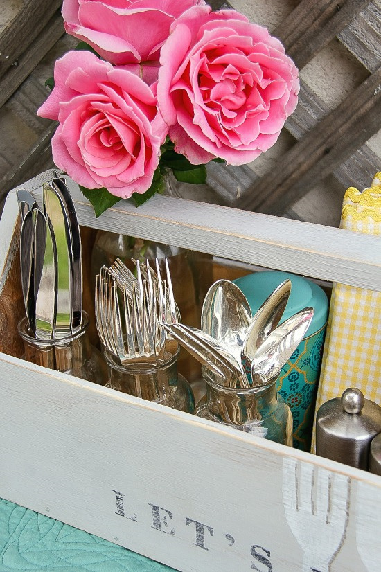 utensils in jars being stored in a grey wood vintage caddy outside