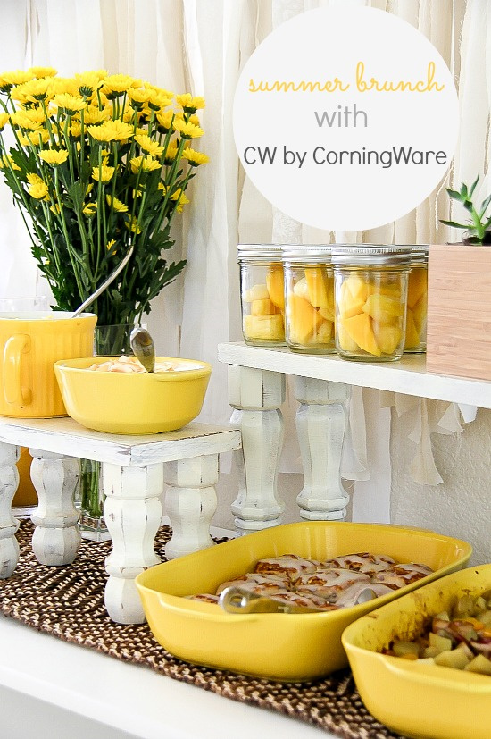 summer yellow brunch table with fresh flowers, fruit in jars, cinnamon buns, and dip