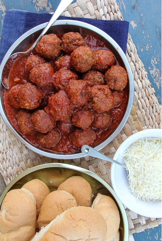 meatballs in a red sauce with hot dog buns and cheese