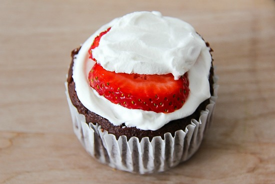 chocolate cupcakes topped with whipped cream and strawberries