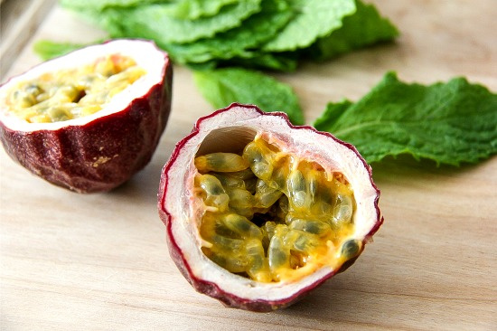 passion fruit cut in half on a cutting board with fresh mint