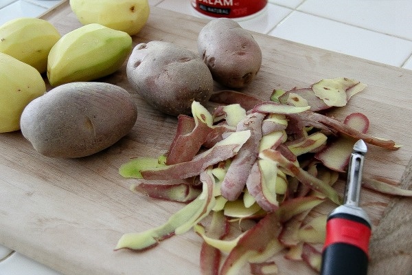 purple potatoes being peeled on a cutting board