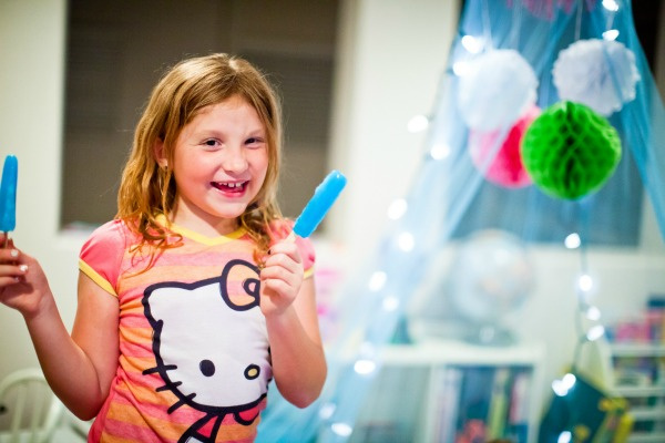 a girl eating blue popsicles