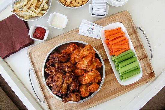 wings, fries, carrot sticks, celery, pretzels and condiments on a table