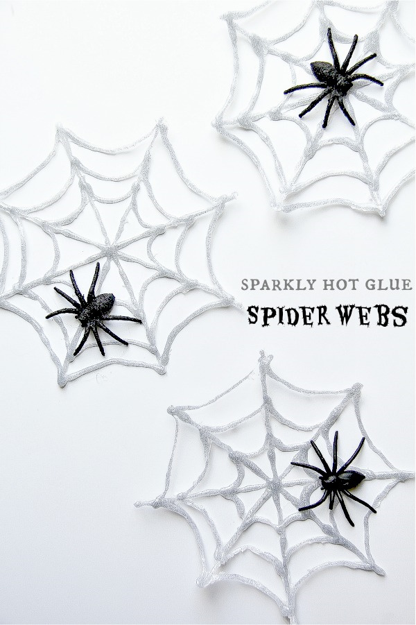 spiderwebs made of hot glue and glitter with black plastic spiders on them